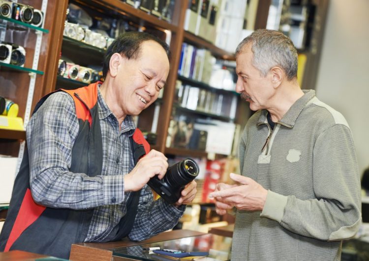 Shop owner explaining camera specs to a potential customer